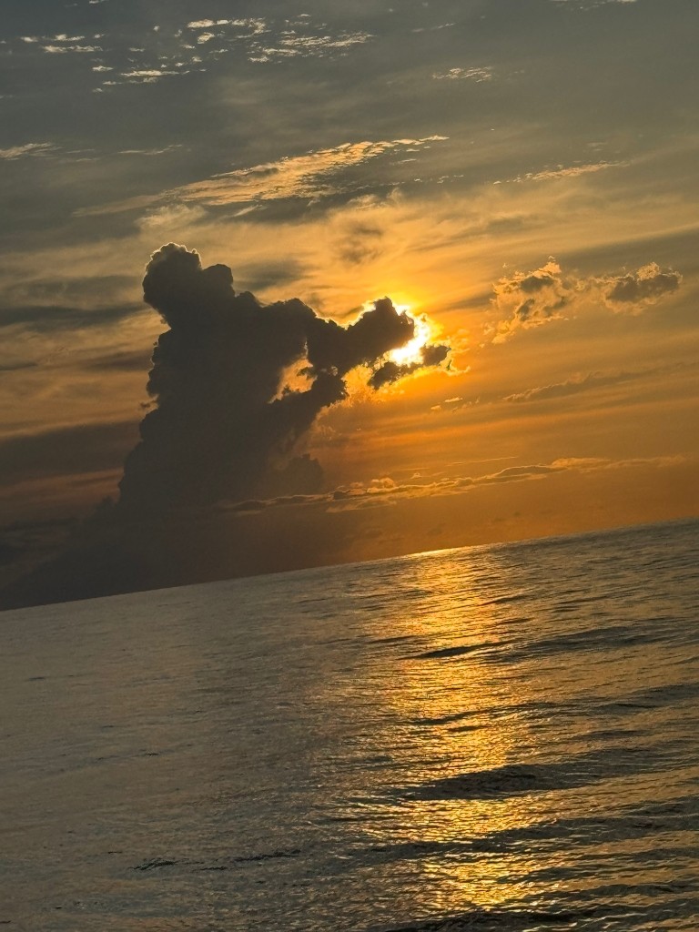 Dramatic sunset cloudburst with golden sun rays over water
