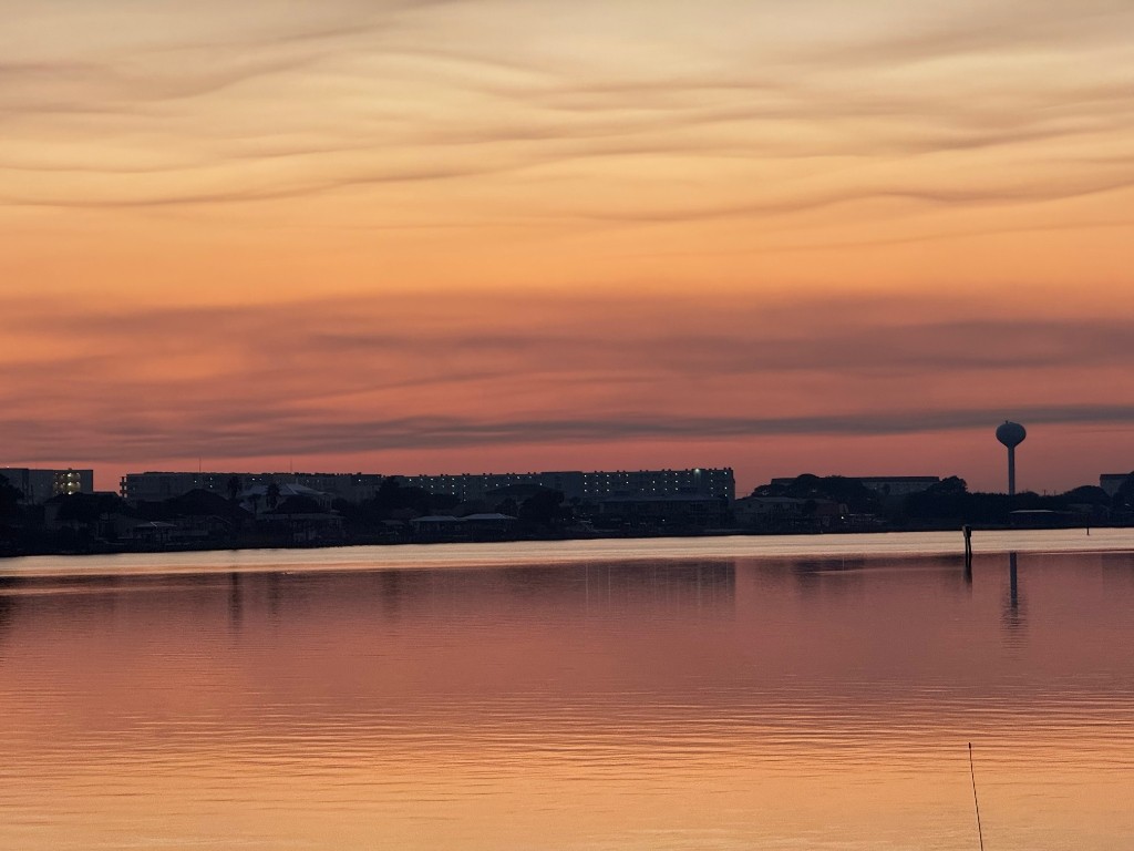 Tranquil glass-calm water reflecting pink and gold sunset sky